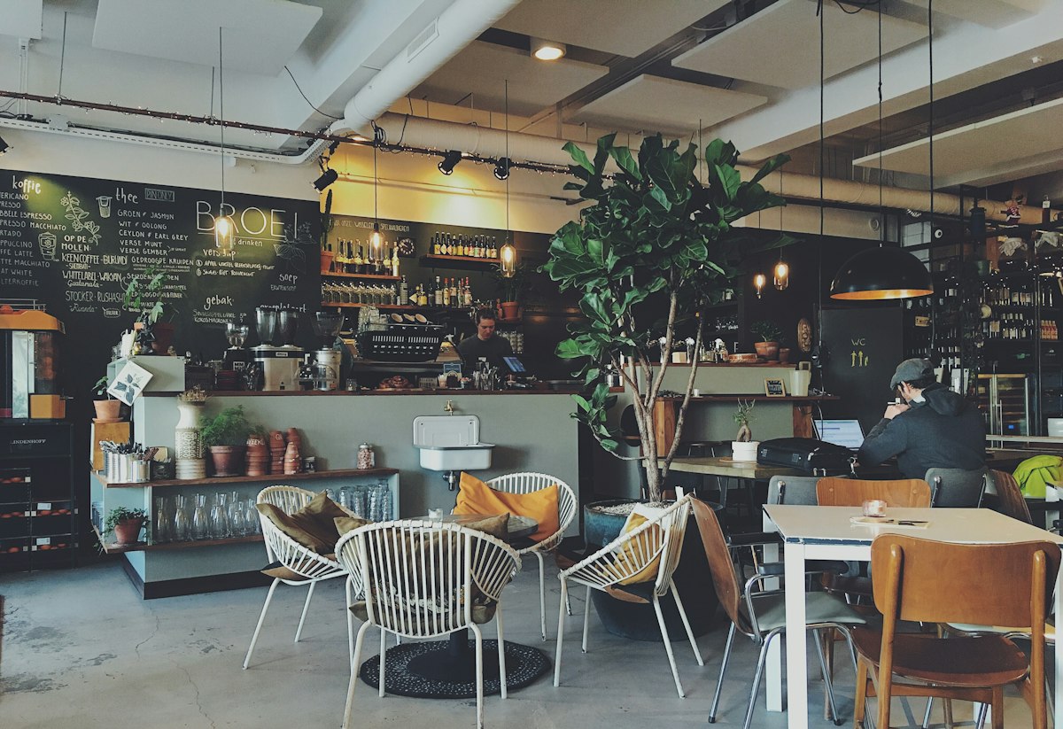 Café animé où des clients tentent de travailler sur leurs ordinateurs portables